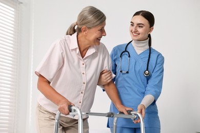 Photo of Nurse helping senior woman with walking frame in clinic