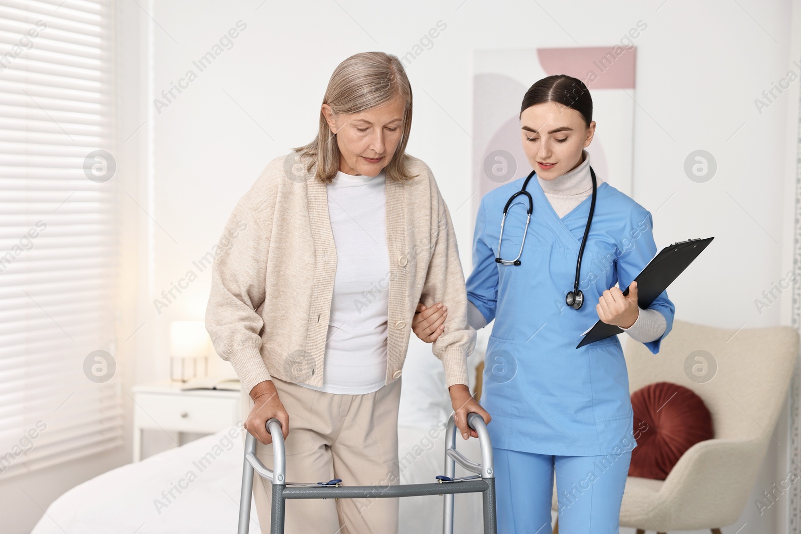 Photo of Nurse helping senior woman with walking frame in clinic