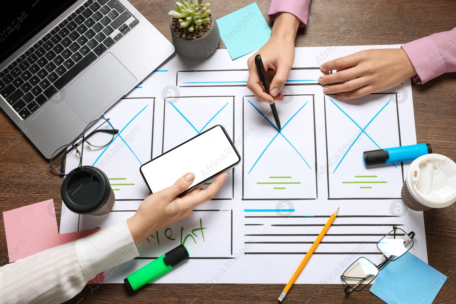 Photo of Developing UI design. Designers creating website wireframe on paper at wooden table, top view