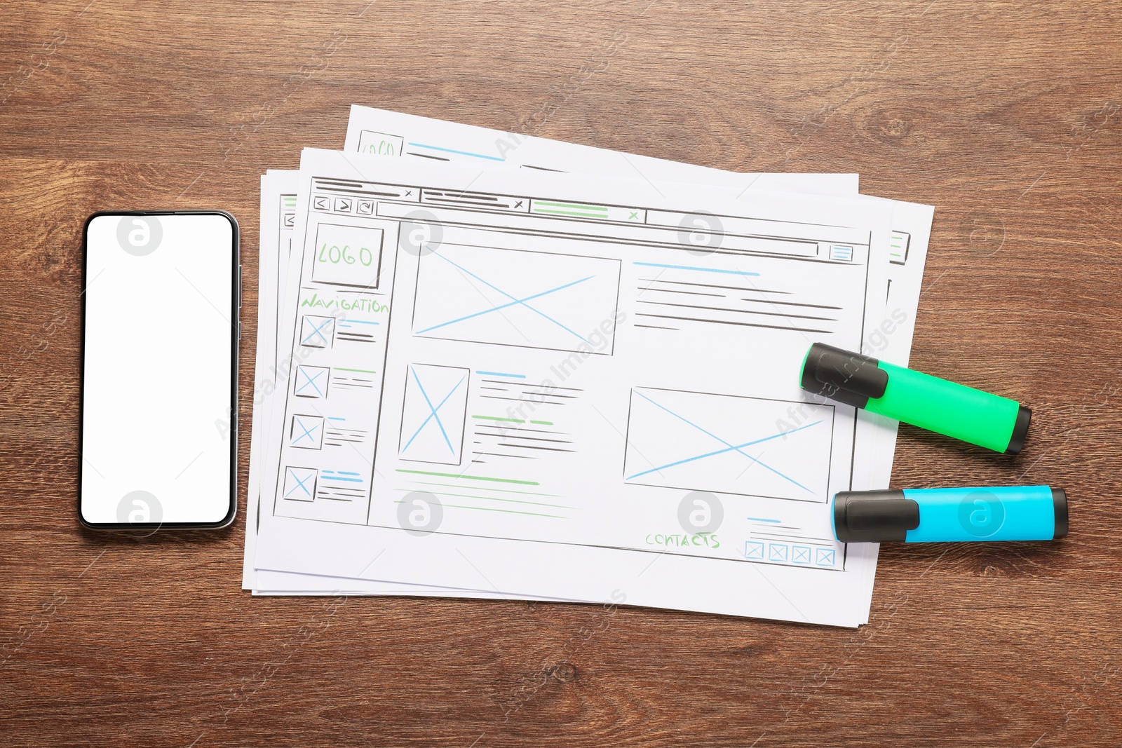 Photo of Developing UI design. Sketches of website wireframes, smartphone and felt pens on wooden table, top view