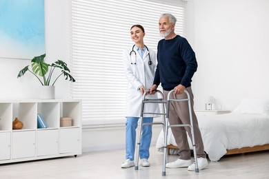 Photo of Doctor helping senior man with walking frame in clinic