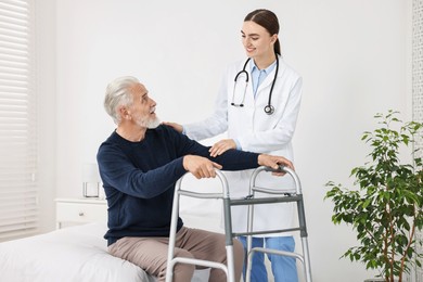 Photo of Doctor helping senior man with walking frame in clinic