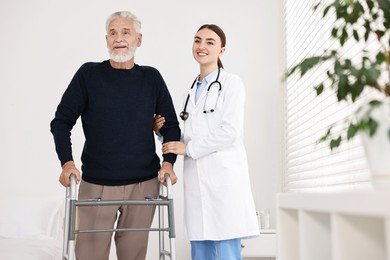 Photo of Doctor helping senior man with walking frame in clinic