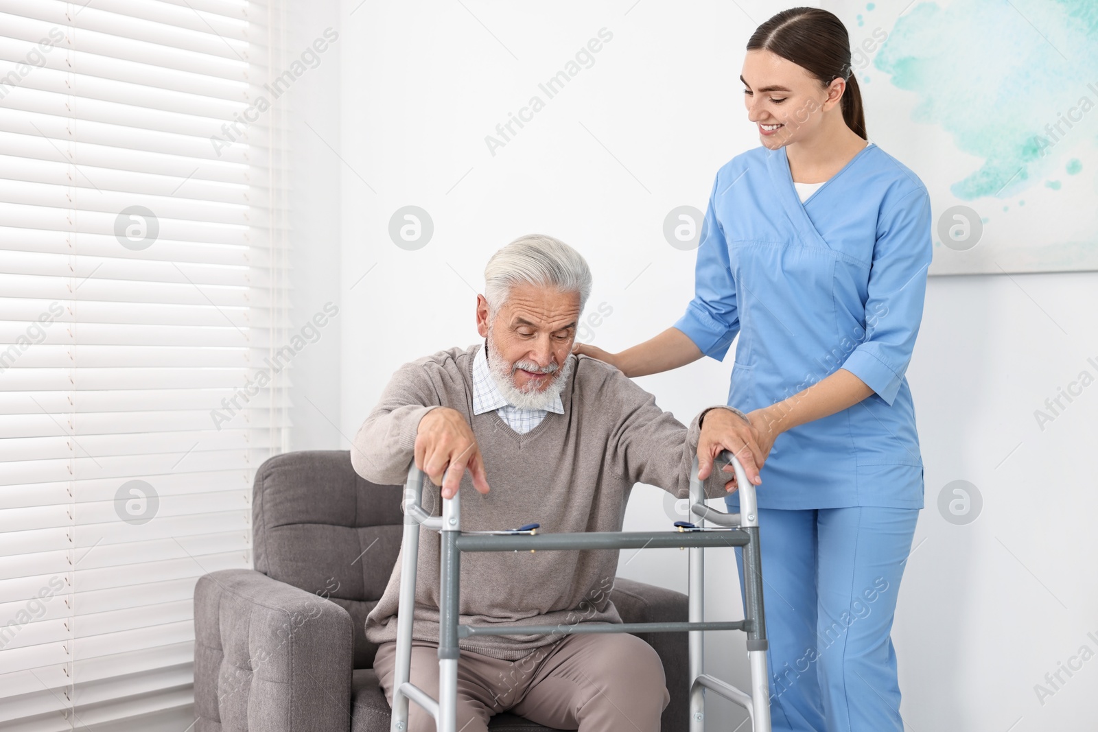 Photo of Nurse helping senior man with walking frame in clinic