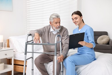 Doctor consulting senior patient with walking frame in hospital ward