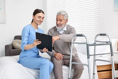 Doctor consulting senior patient with walking frame in hospital ward