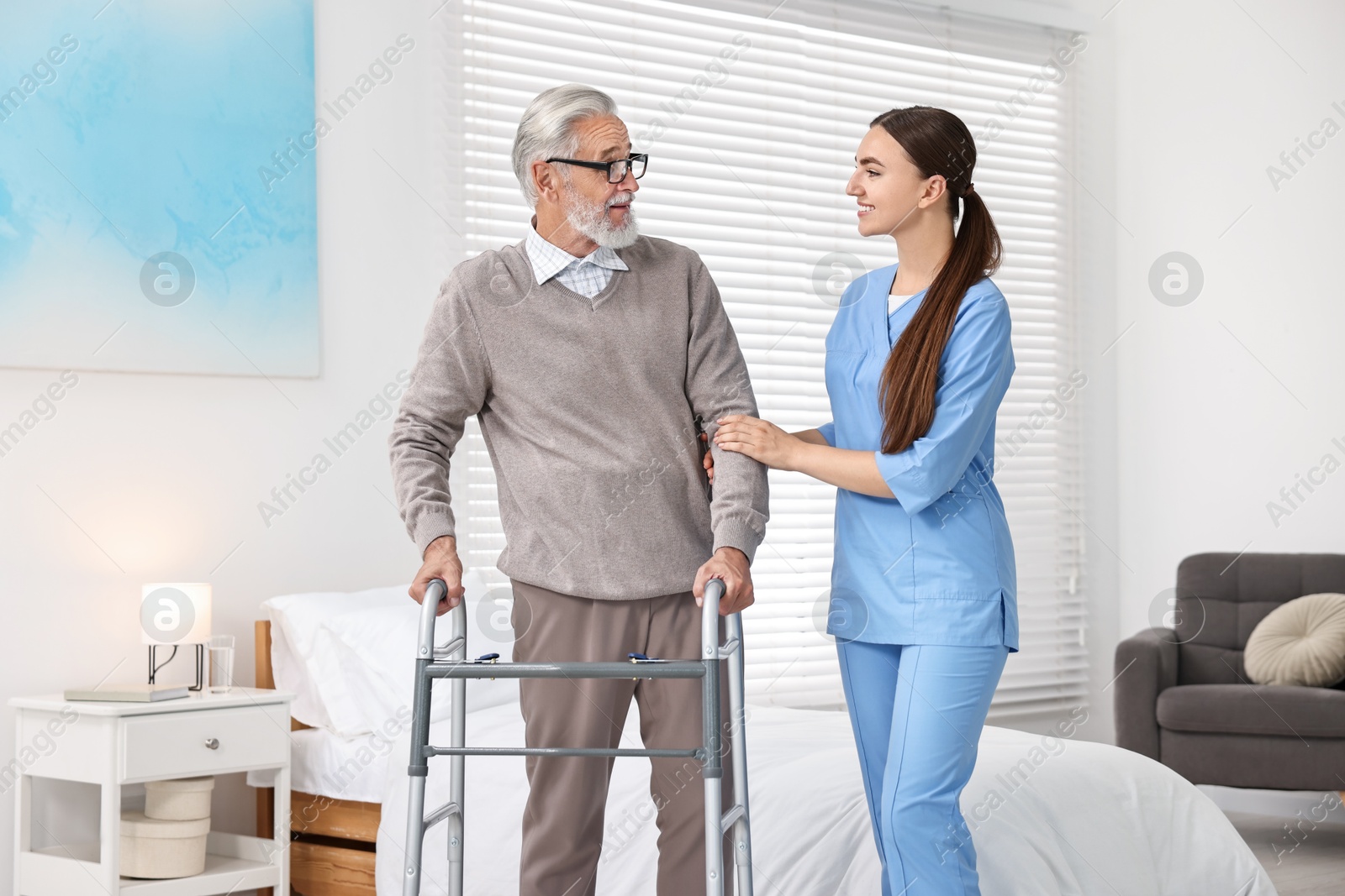 Photo of Nurse helping senior man with walking frame in clinic