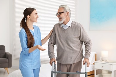 Photo of Nurse helping senior man with walking frame in clinic