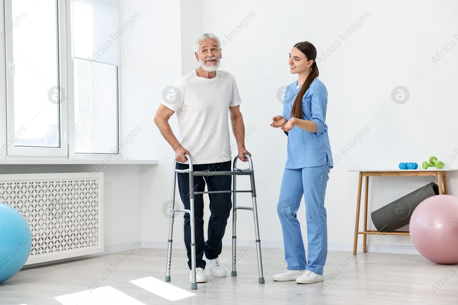 Photo of Nurse talking to senior man with walking frame in clinic