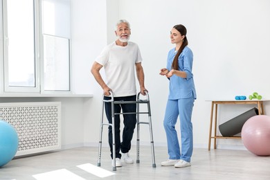 Nurse talking to senior man with walking frame in clinic