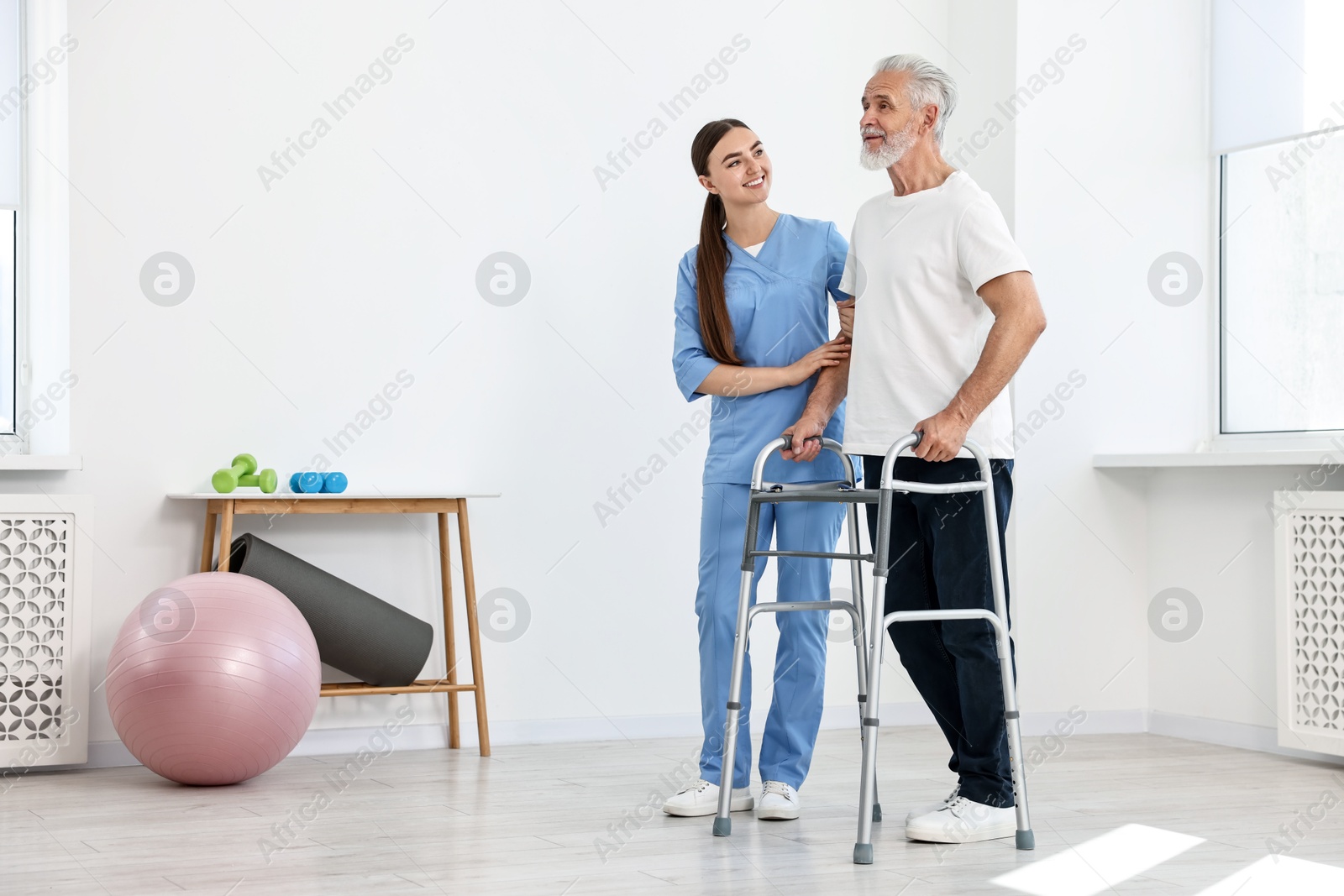 Photo of Nurse helping senior man with walking frame in clinic