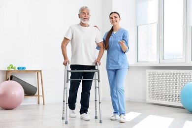 Photo of Nurse helping senior man with walking frame in clinic