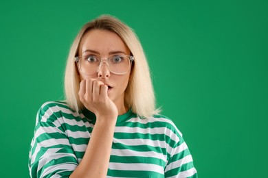 Portrait of scared woman on green background, space for text