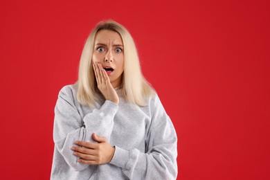 Portrait of scared woman on red background, space for text