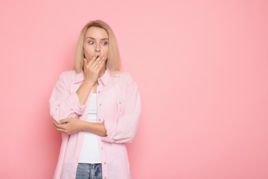 Portrait of scared woman on pink background, space for text