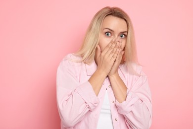 Portrait of scared woman on pink background