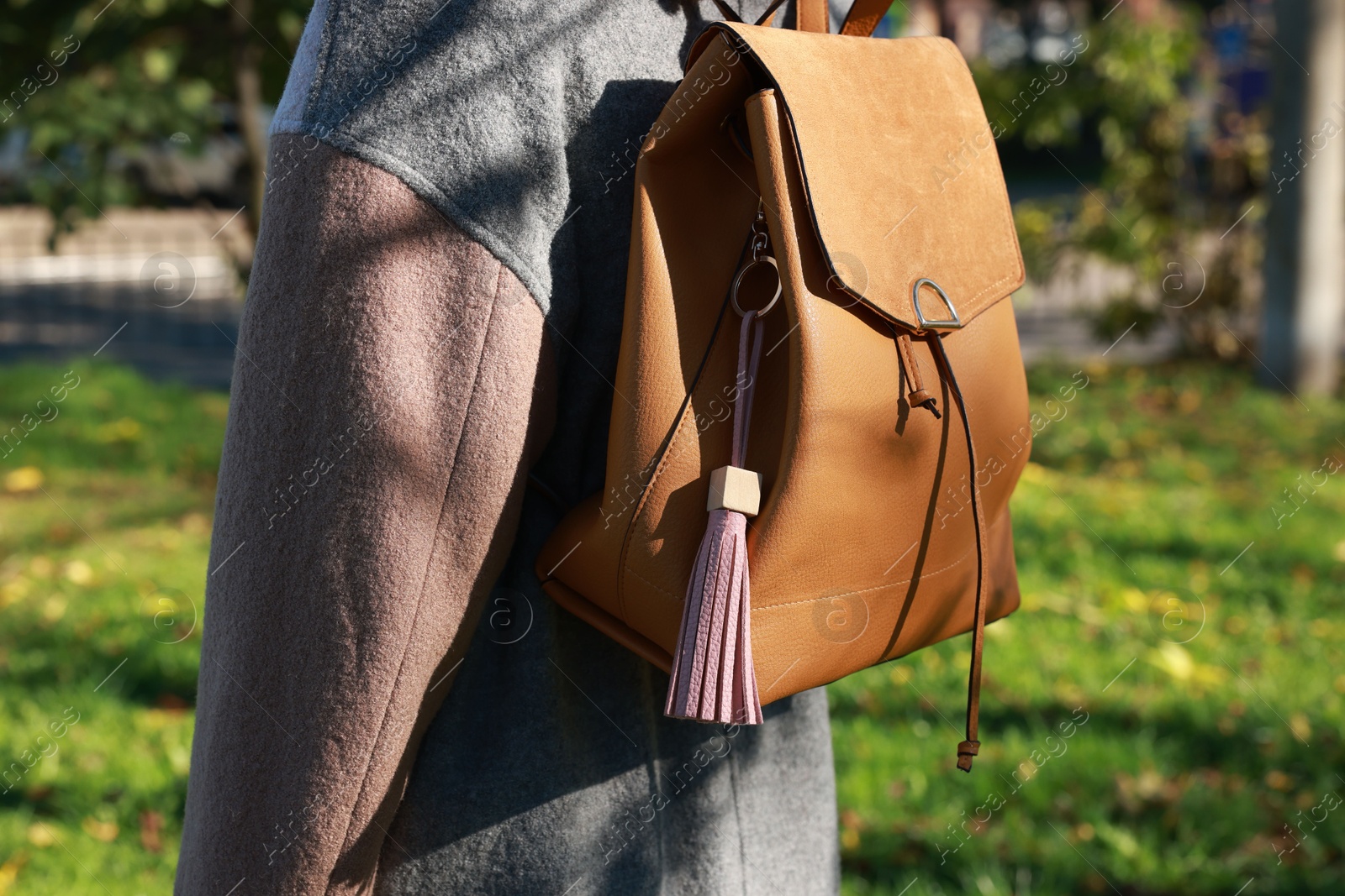 Photo of Woman with pink leather keychain on her backpack outdoors, closeup