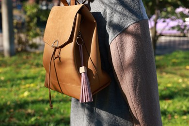 Photo of Woman with pink leather keychain on her backpack outdoors, closeup