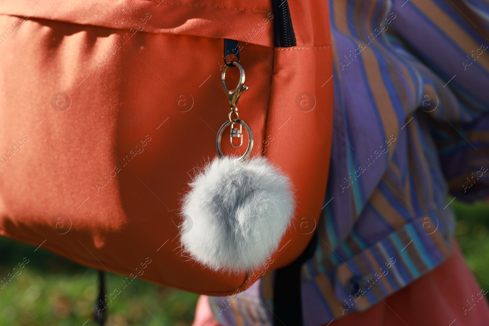 Photo of Woman with faux fur keychain on her backpack outdoors, closeup