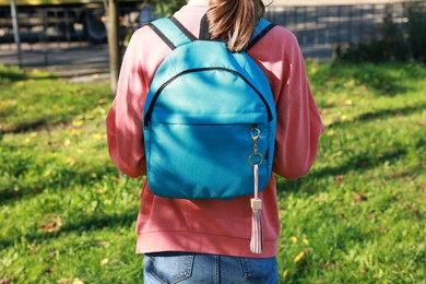 Photo of Woman with pink leather keychain on her backpack outdoors, closeup