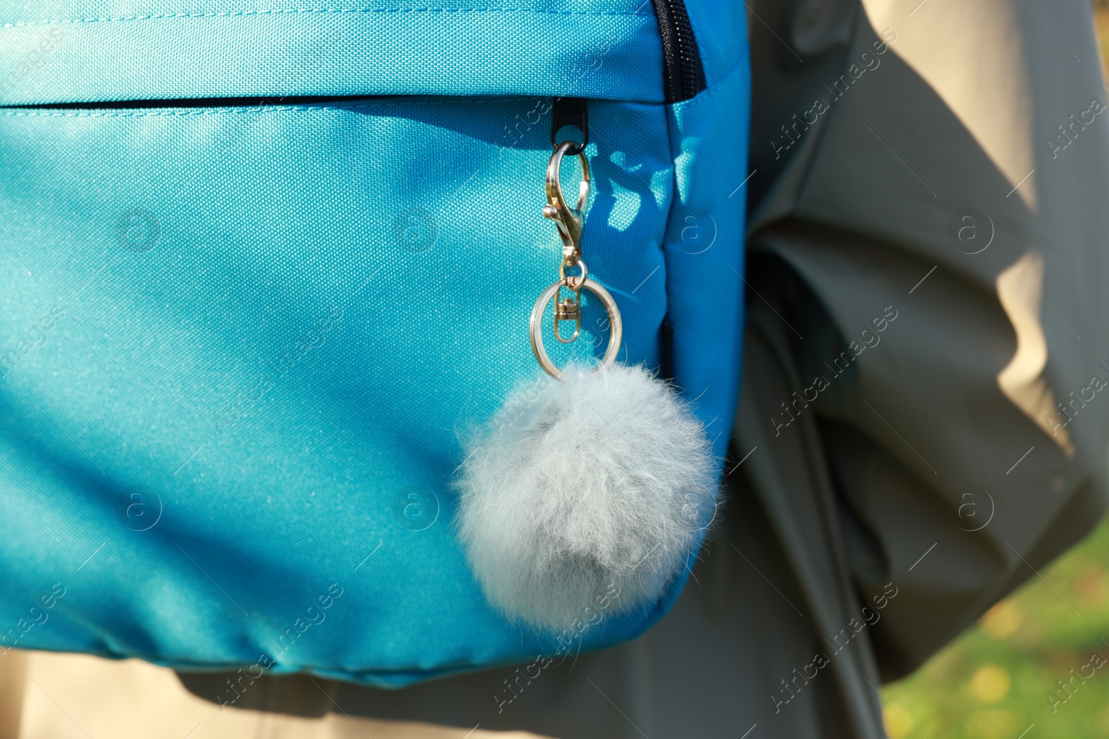 Photo of Woman with faux fur keychain on her backpack outdoors, closeup