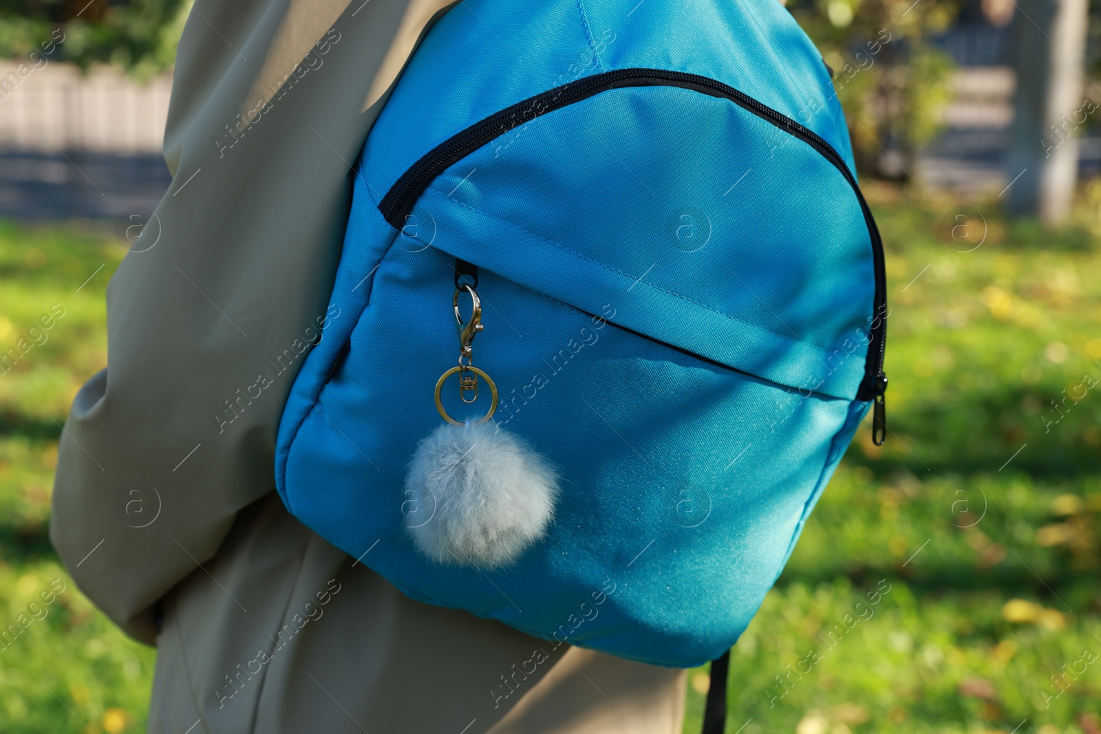 Photo of Woman with faux fur keychain on her backpack outdoors, closeup