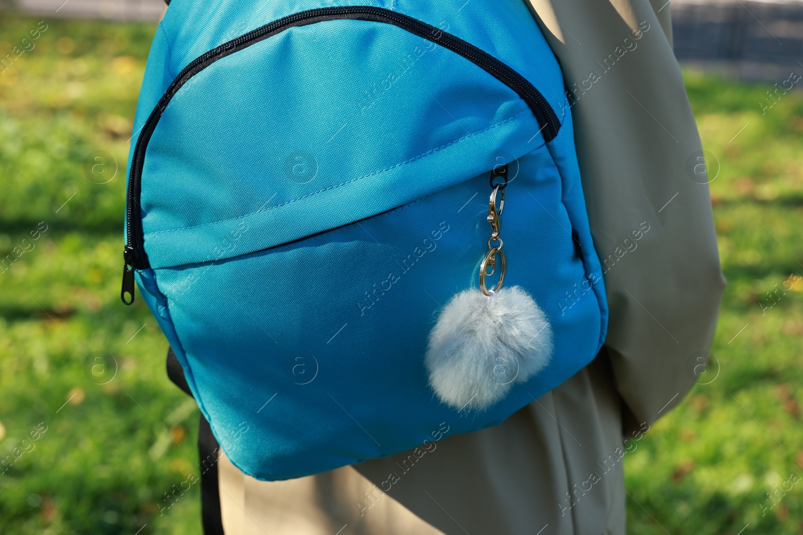 Photo of Woman with faux fur keychain on her backpack outdoors, closeup