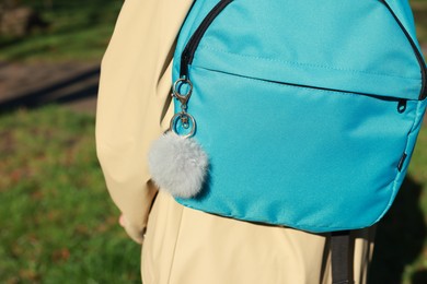 Photo of Woman with faux fur keychain on her backpack outdoors, closeup