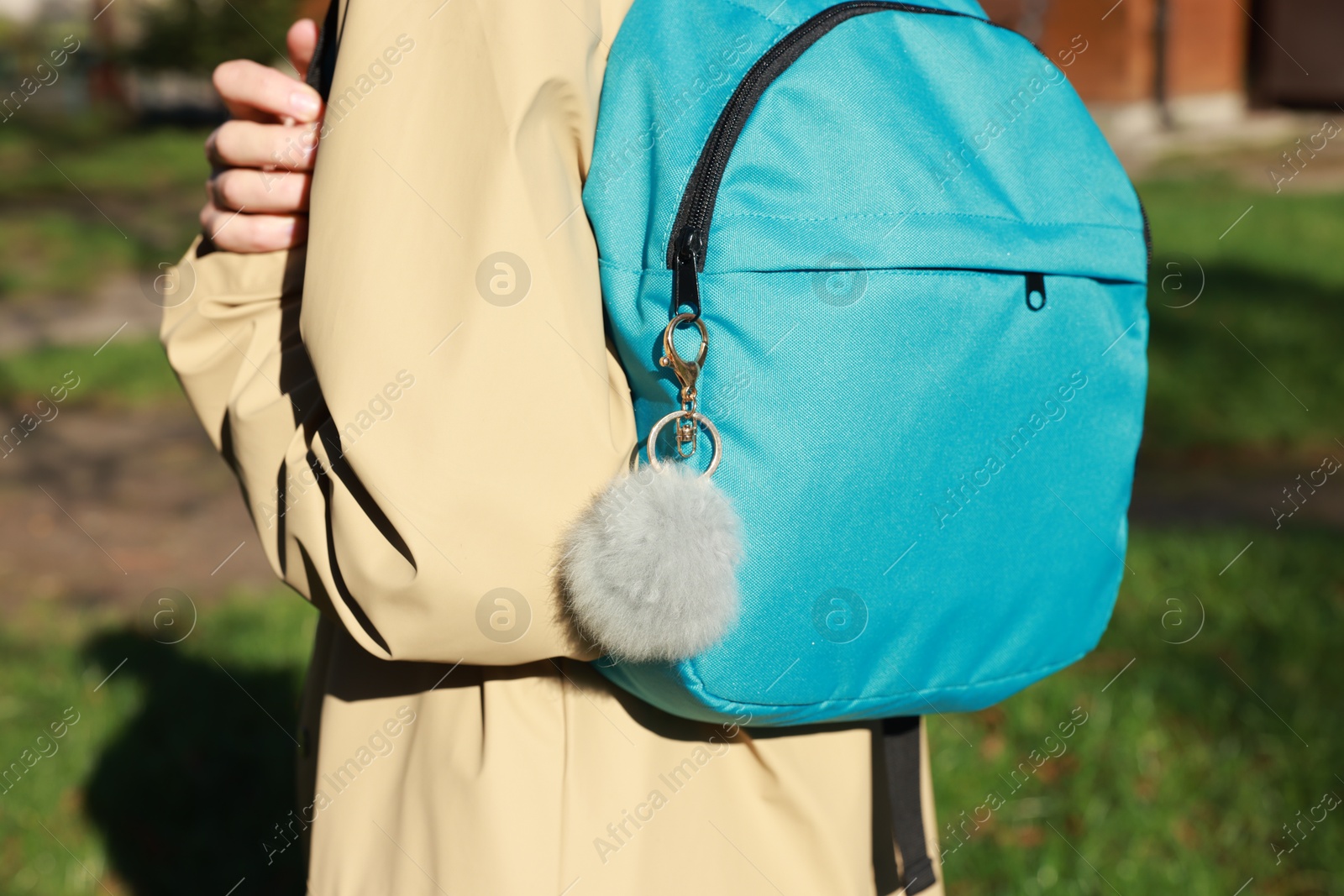 Photo of Woman with faux fur keychain on her backpack outdoors, closeup