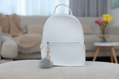 Photo of Stylish backpack with faux fur keychain on soft surface indoors