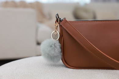 Photo of Stylish bag with faux fur keychain on soft surface indoors, closeup. Space for text