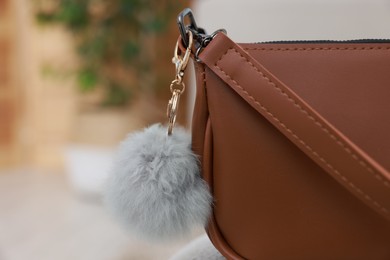 Photo of Stylish bag with faux fur keychain indoors, closeup