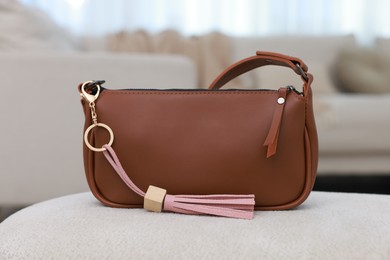 Photo of Stylish bag with pink leather keychain on soft surface indoors