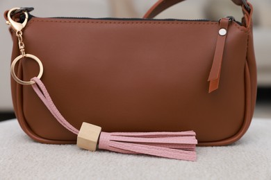 Photo of Stylish bag with pink leather keychain on soft surface indoors, closeup