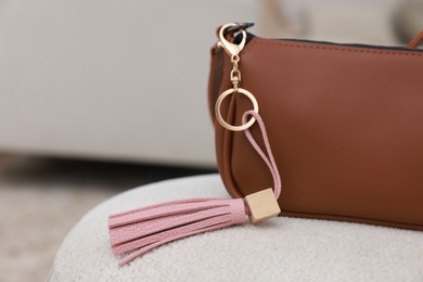 Photo of Stylish bag with pink leather keychain on soft surface indoors, closeup