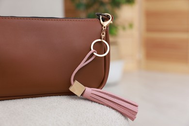 Photo of Stylish bag with pink leather keychain on soft surface indoors, closeup