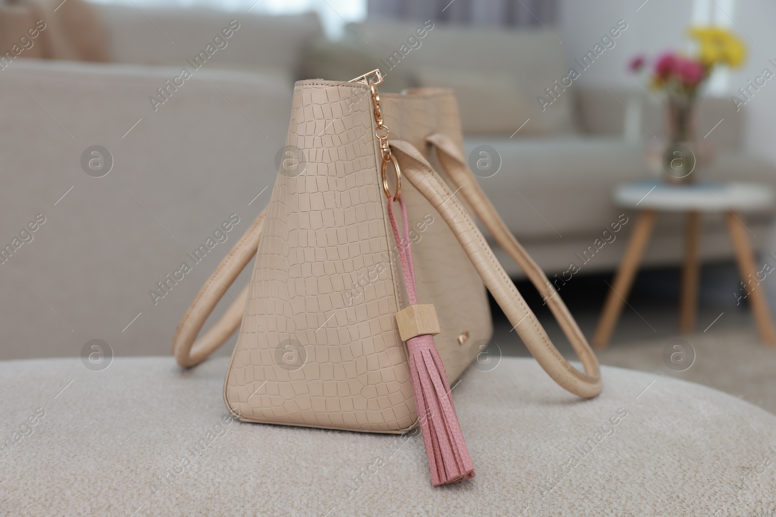 Photo of Stylish bag with pink leather keychain on soft surface indoors, closeup