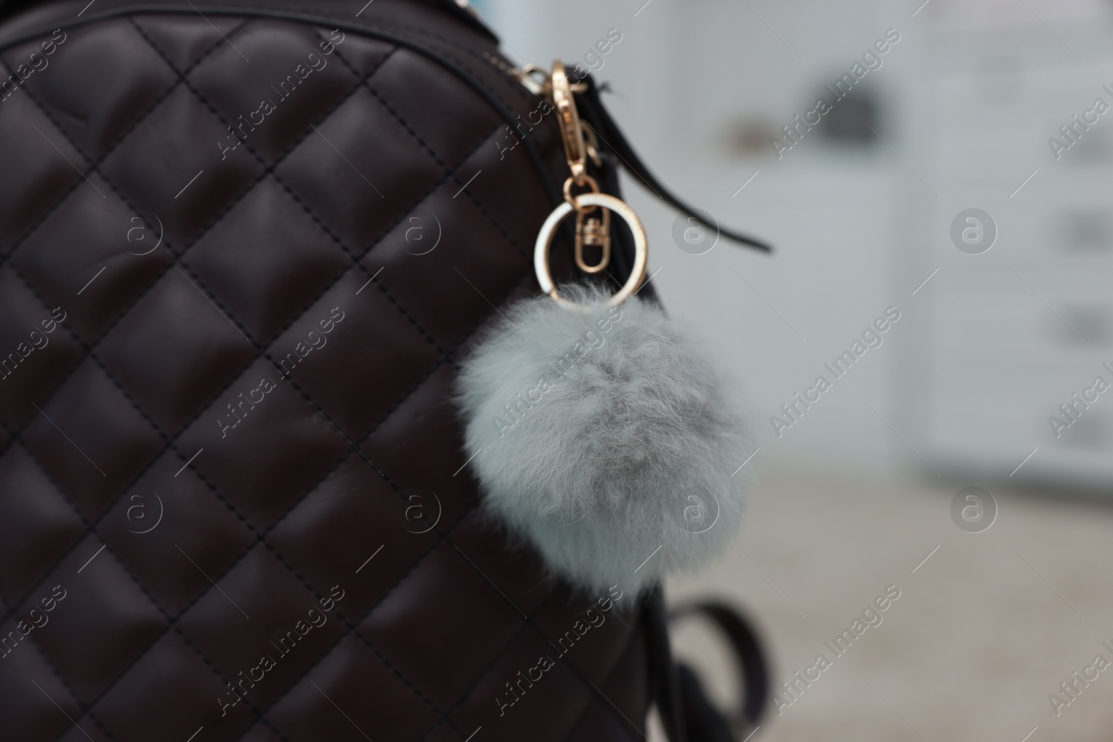 Photo of Stylish backpack with faux fur keychain indoors, closeup. Space for text