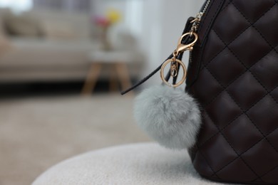 Stylish backpack with faux fur keychain on soft surface indoors, closeup. Space for text