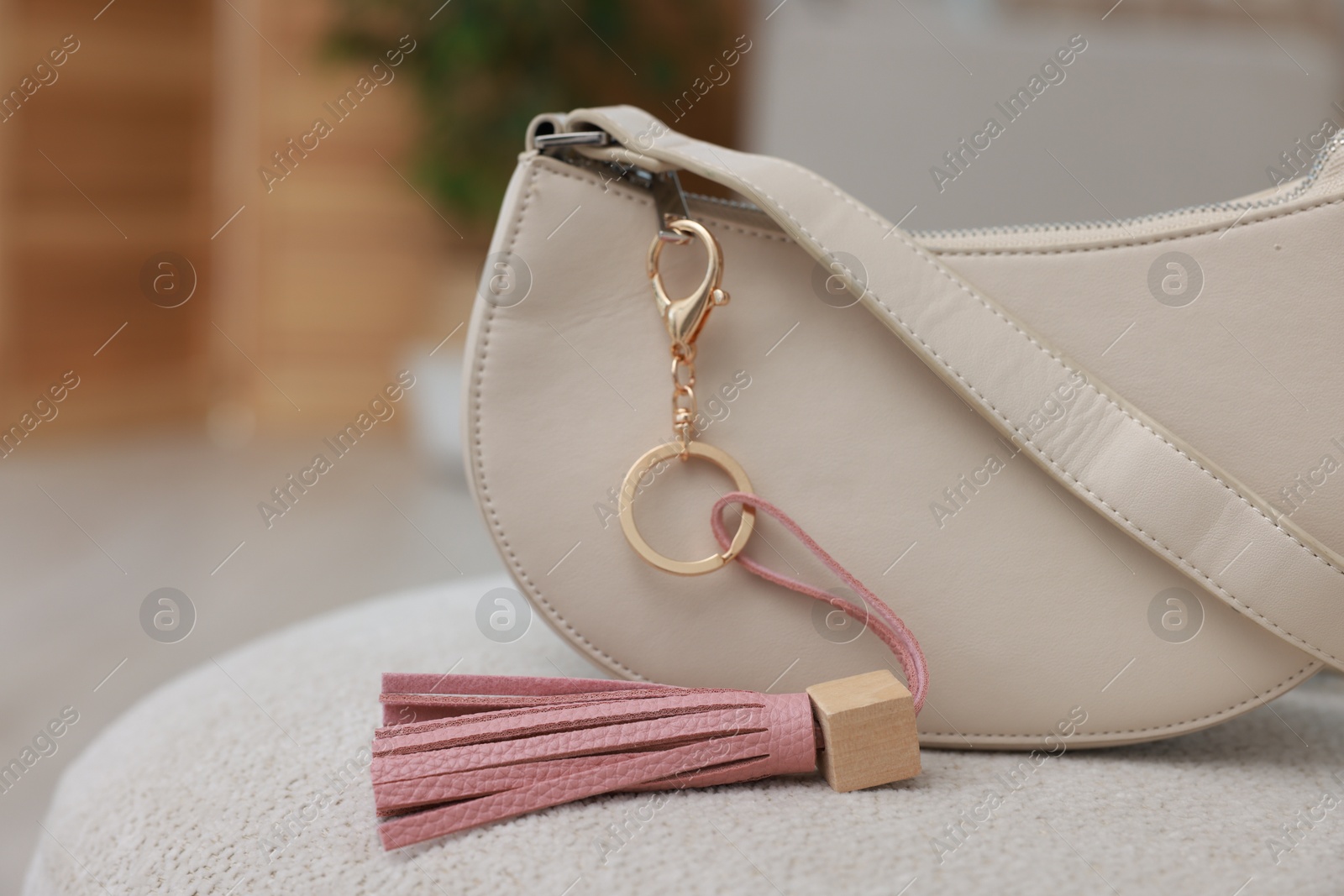 Photo of Stylish bag with pink leather keychain on soft surface indoors, closeup