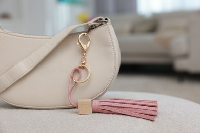 Photo of Stylish bag with pink leather keychain on soft surface indoors, closeup