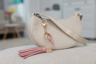 Photo of Stylish bag with pink leather keychain on soft surface indoors, closeup