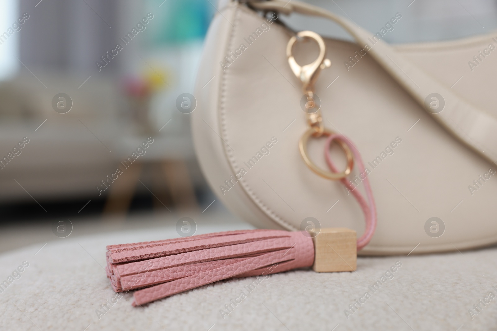 Photo of Stylish bag with pink leather keychain on soft surface indoors, closeup. Selective focus