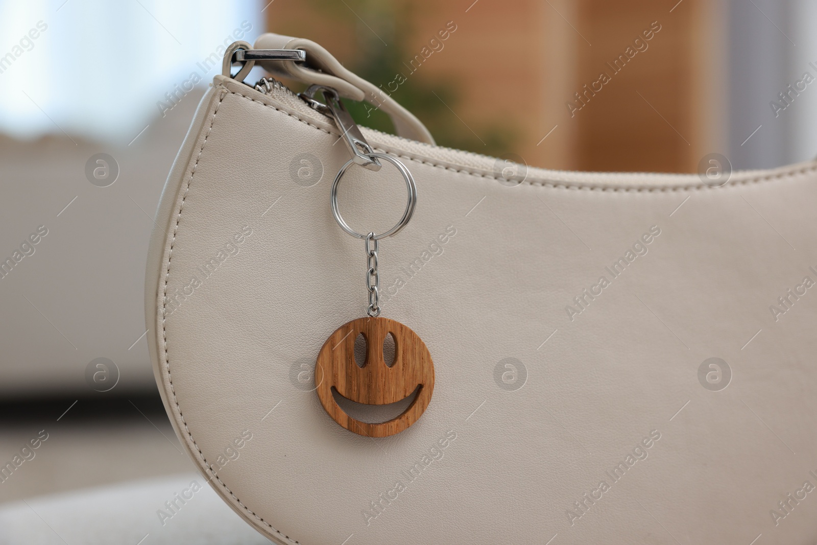 Photo of Stylish bag with wooden keychain in shape of smiley face indoors, closeup