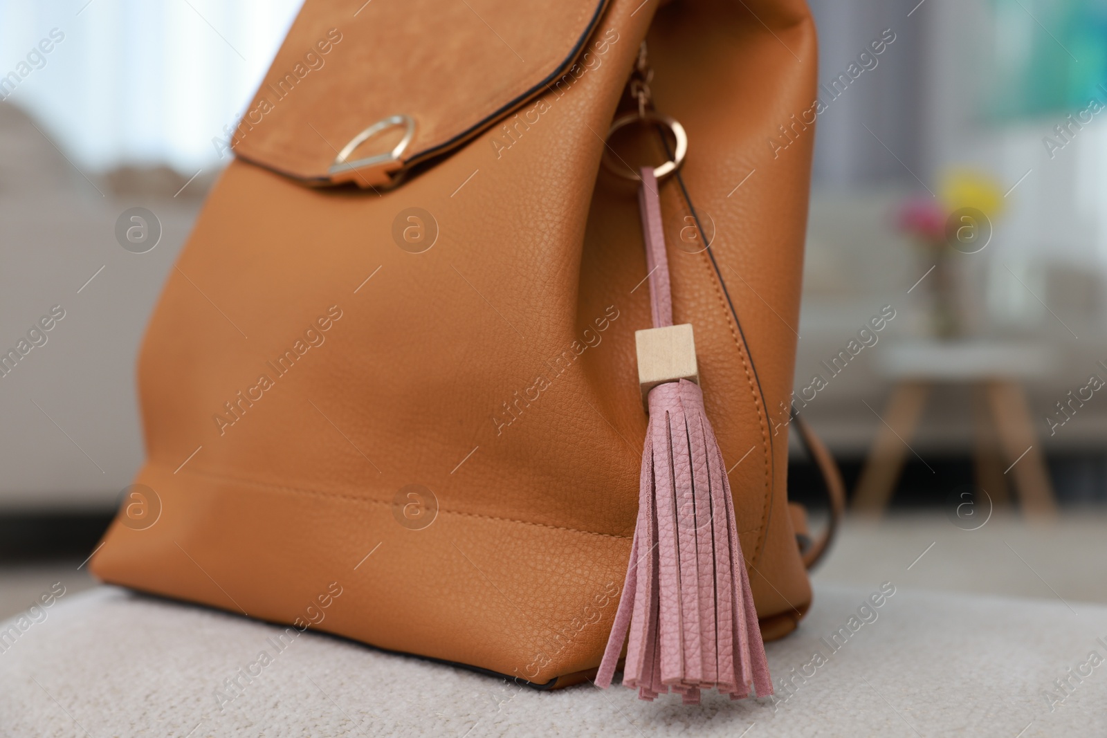 Photo of Backpack with pink leather keychain on soft surface indoors, closeup