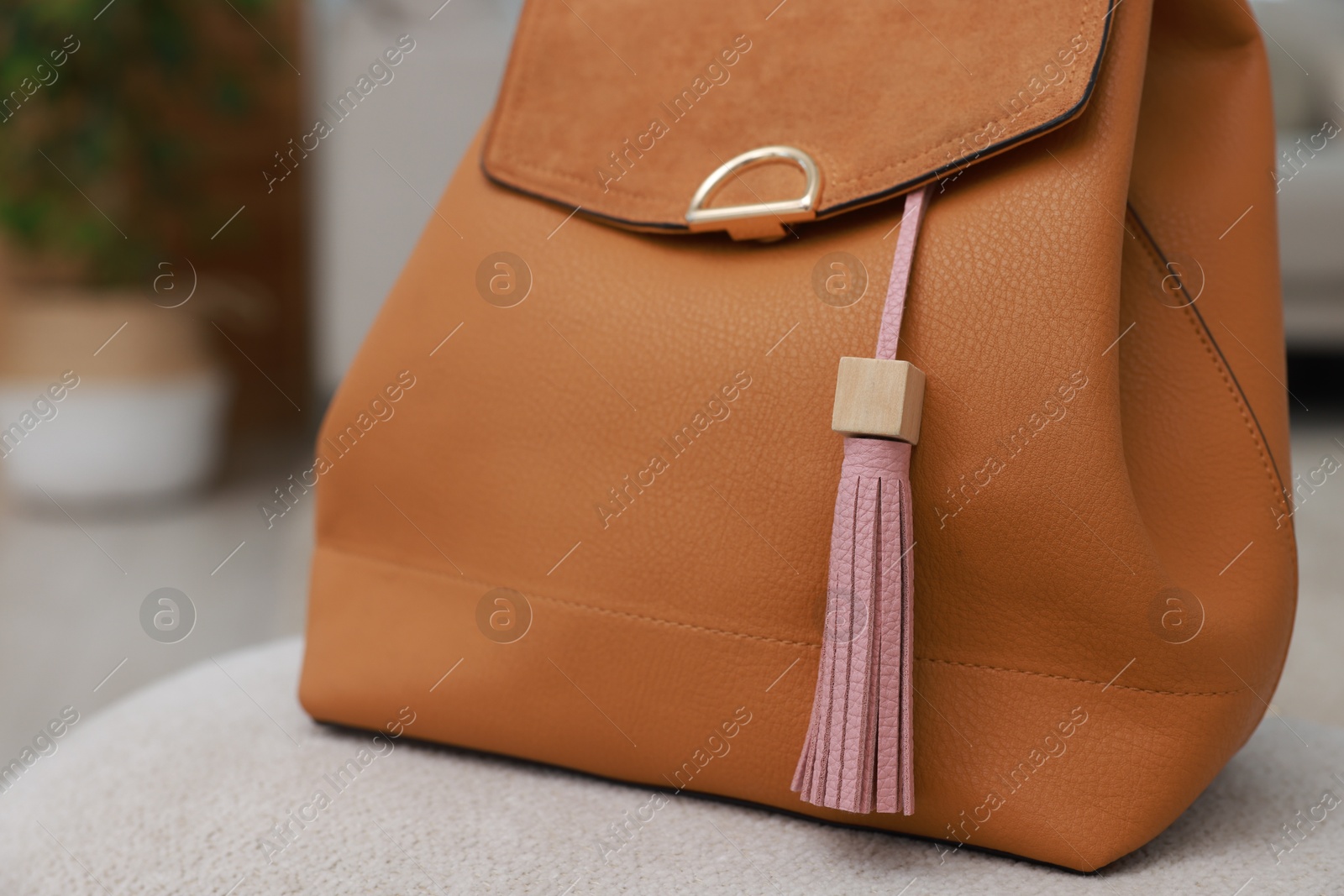 Photo of Backpack with pink leather keychain on soft surface indoors, closeup