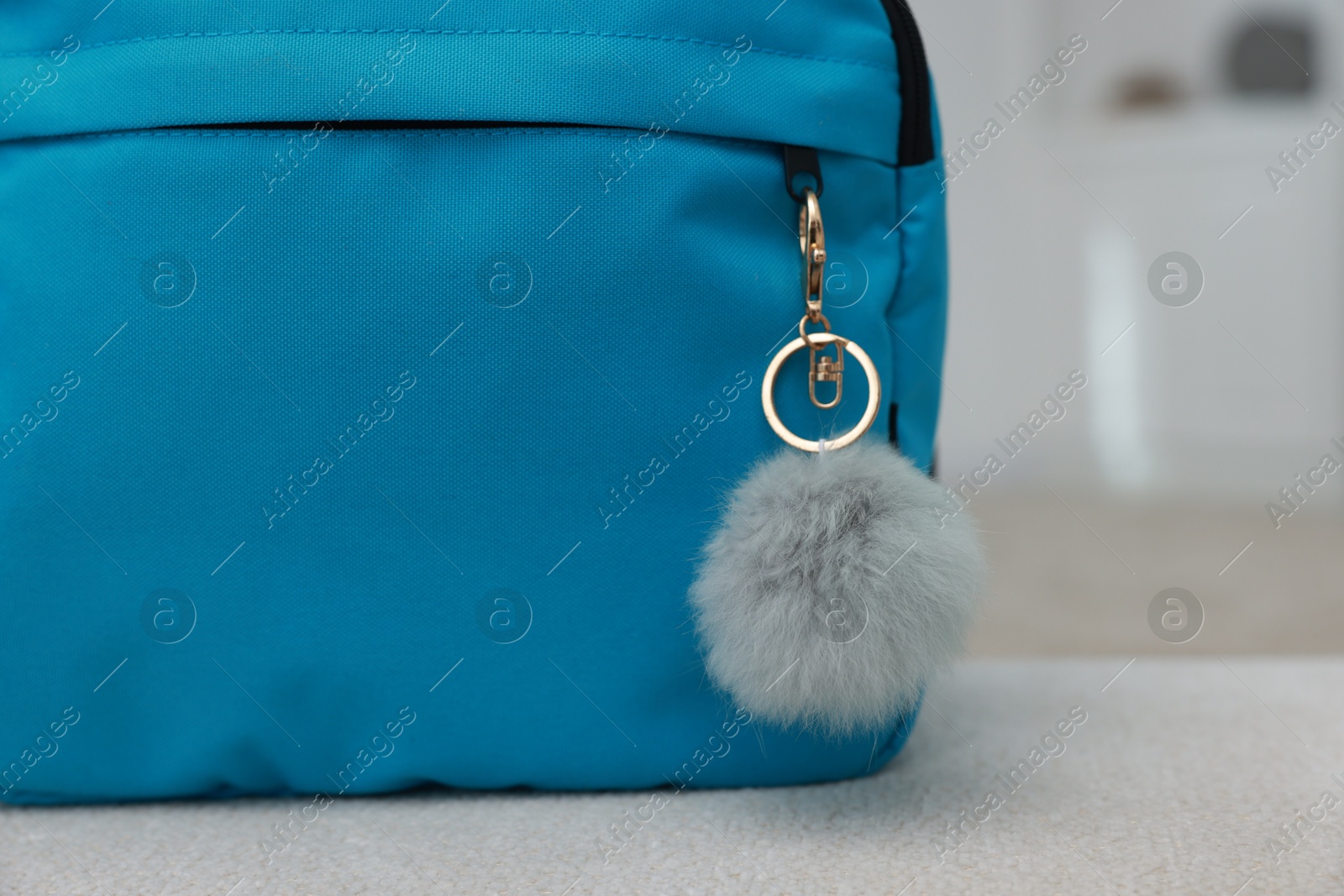 Photo of Backpack with faux fur keychain on soft surface indoors, closeup