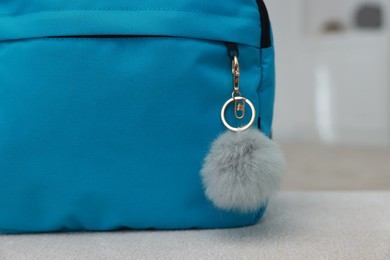 Photo of Backpack with faux fur keychain on soft surface indoors, closeup