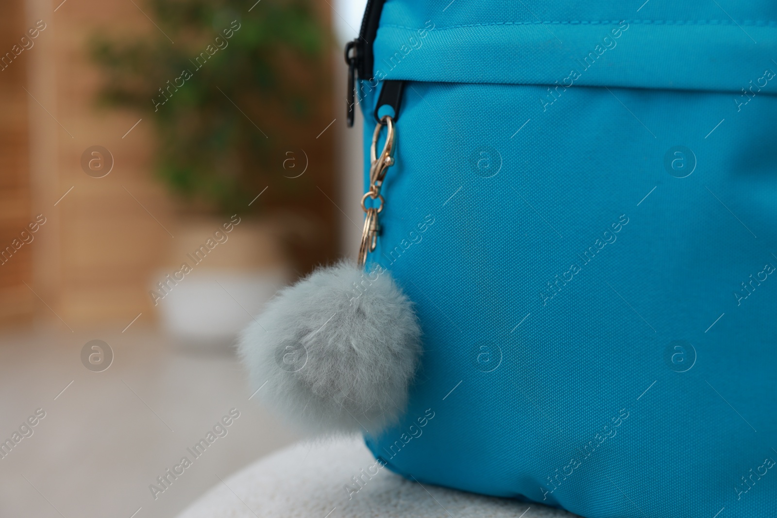 Photo of Backpack with faux fur keychain on soft surface indoors, closeup