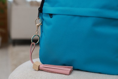 Photo of Backpack with pink leather keychain on soft surface indoors, closeup